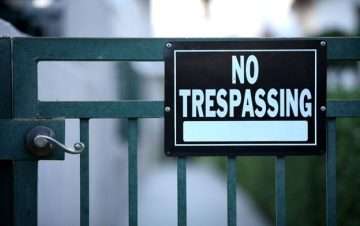 black no trespassing sign on a green gate