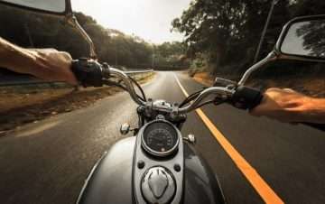 Black motorcycle first-person view driving down road.
