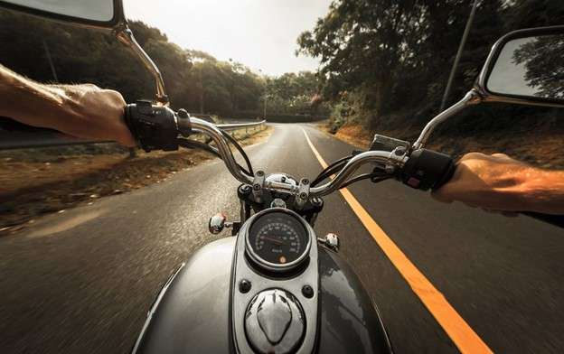 Black motorcycle first-person view driving down road.