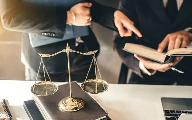 lawyers at at table with scales of justice