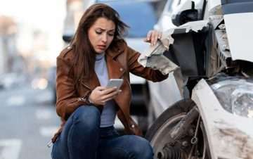 Woman taking picture of car with damage. How to properly document evidence for your case after a car accident.