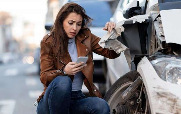 Woman taking picture of car with damage. How to properly document evidence for your case after a car accident.