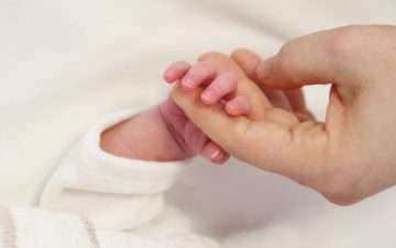 adult hand holding a newborn's hand. Can You File A Medical Malpractice Claim For Birth Injuries?