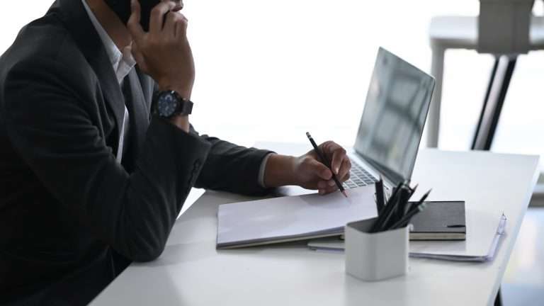Man at desk with pen and paper and computer at desk. We explain 5 common mistakes to avoid during your personal injury case.