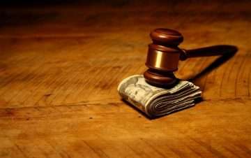 Judge's gavel on top of money. How long do you need to wait for a settlement check in New York?