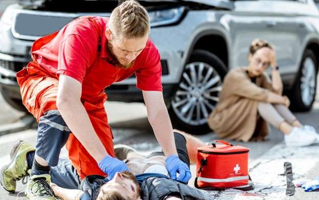 Male paramedic assisting unconsciousness man, woman in background leaning on car with concerned look. How to prove fault in a pedestrian accident In New York.