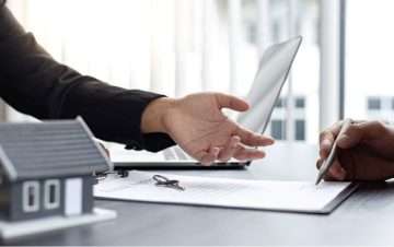 Person with an outstretched hand while other person signs document on table. Premises liability case have a timeframe to file.