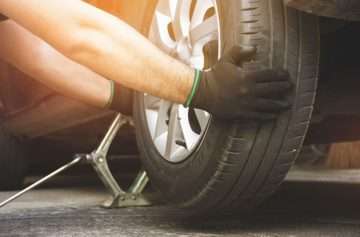 Close up of person holding tire with black gloves on, possible tire defects.