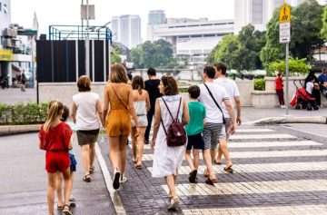 Large group of pedestrians walking through crosswalk.