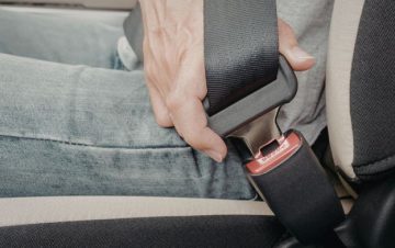 Person buckling in seatbelt. What to know about seat belt defects.