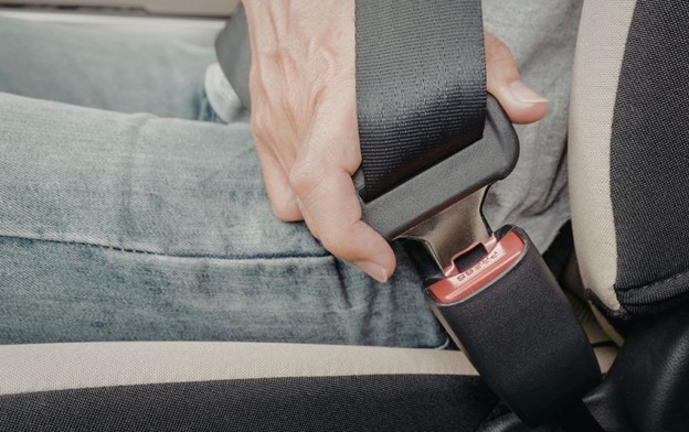 Person buckling in seatbelt. What to know about seat belt defects.