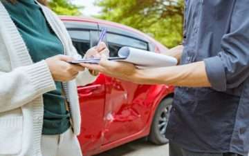 People exchanging insurance details on a clipboard. No-fault insurance.